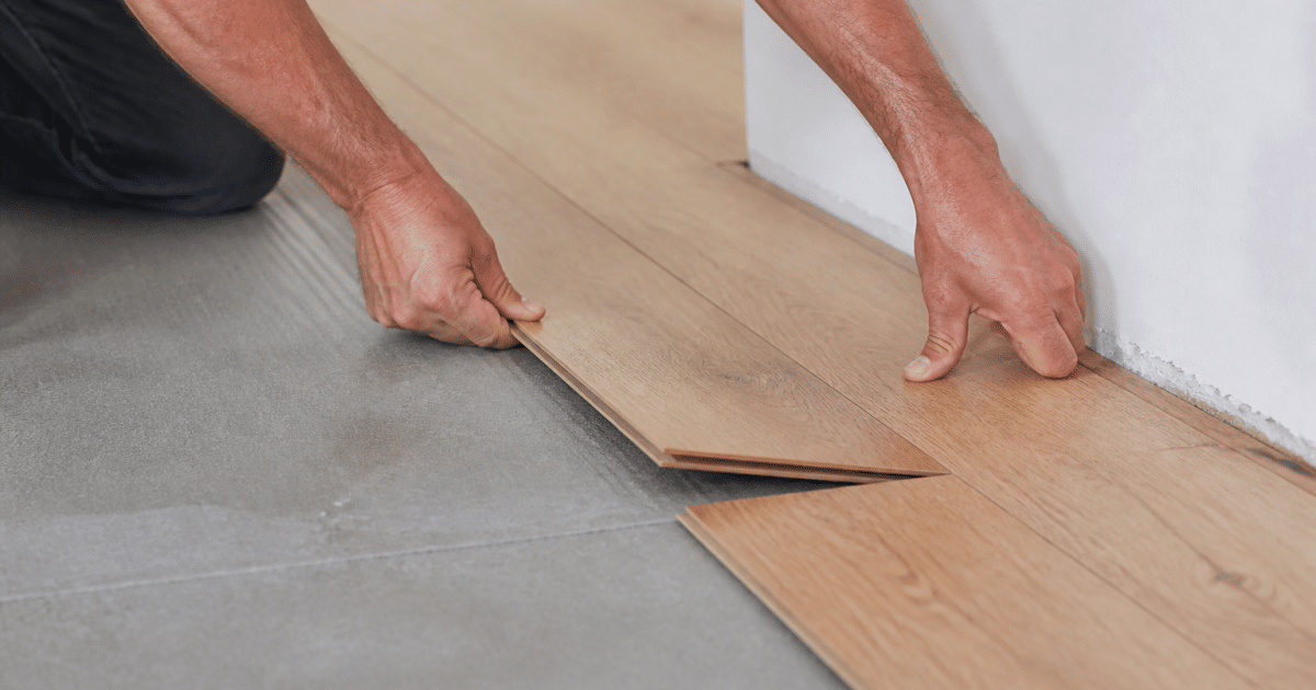 Mains posant des lames de parquet emboitables sur sous-couche grise