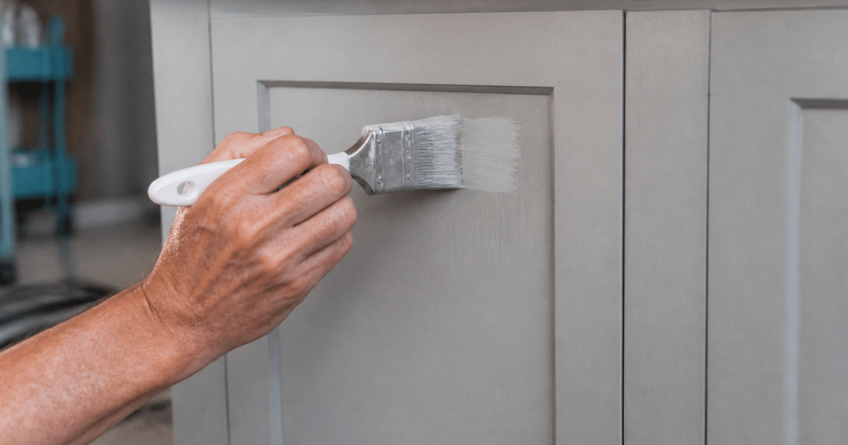 Pinceau appliquant peinture sur facade armoire cuisine fermee