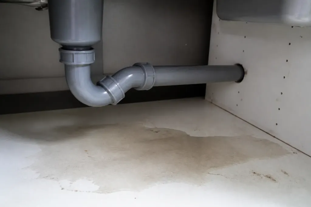 Tuyau gris sous evier avec flaque humide